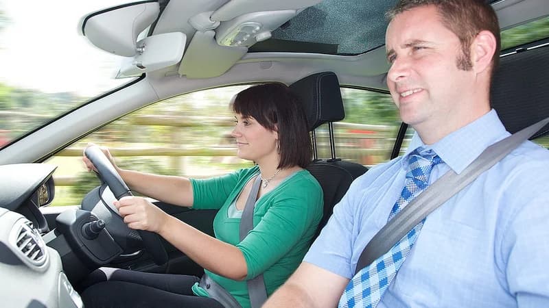 A learner driving a car with an instructor sitting beside them